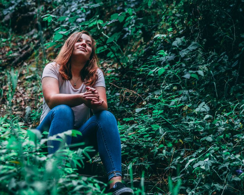 Young woman sitting peacefully among plants